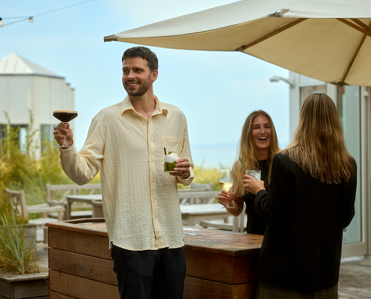 Gæster står med forskellige drinks og griner på Marienlyst Badehotel