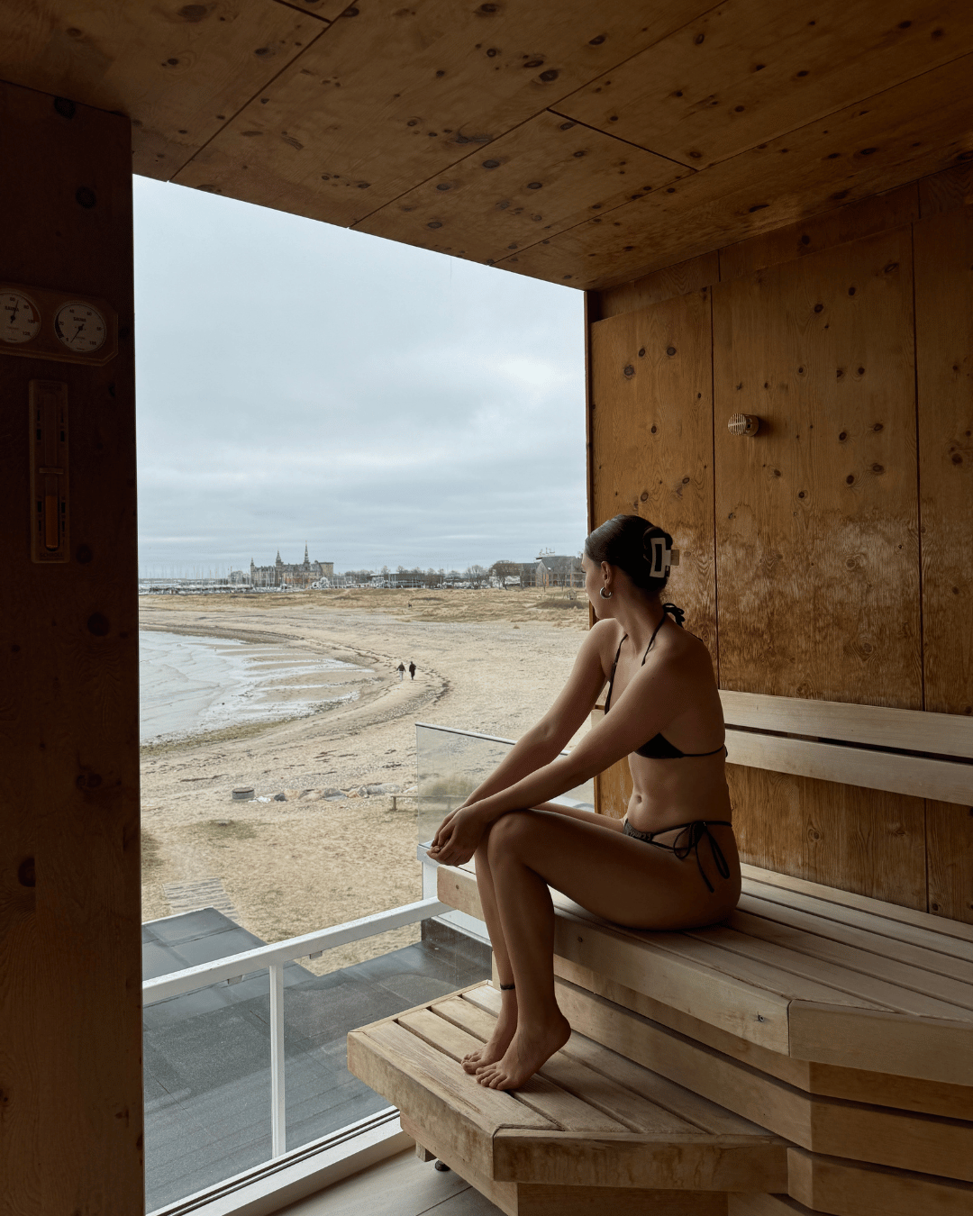 Kvinde sidder i sauna på Marienlyst Badehotel, mens hun kigger ud over Øresund
