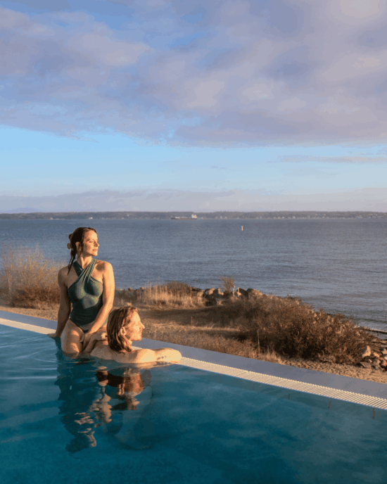 Mand og kvinde i pool med udsigt over Øresund på Marienlyst Badehotel