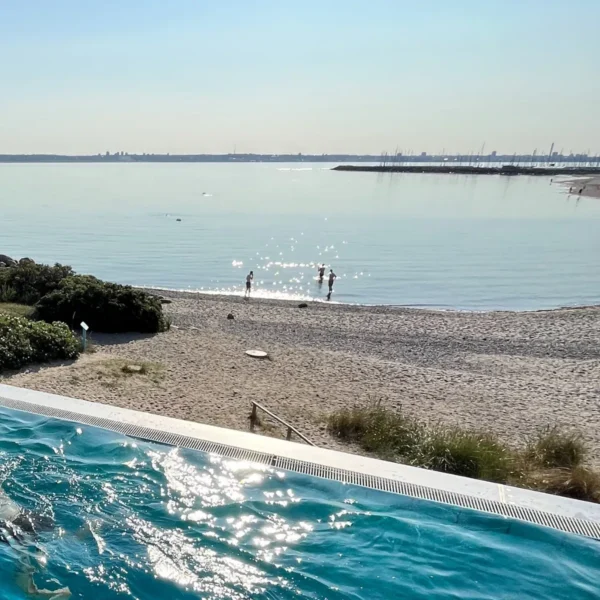 Udsigt fra poolen til stranden og havet ved Marienlyst på en solrig dag